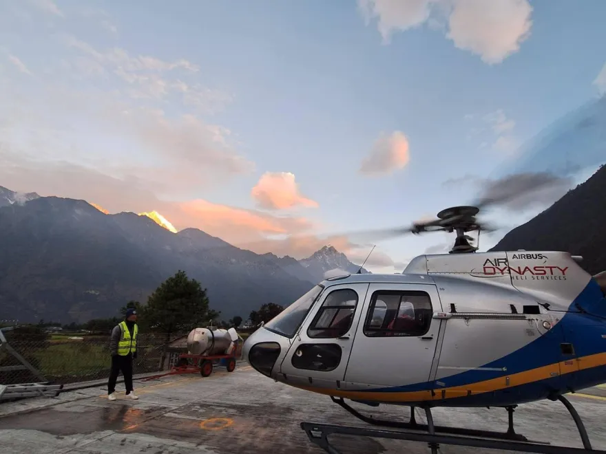 A Helicopter in mountainous region with a person standing nearby