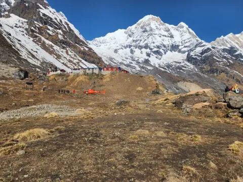 The premium helicopter in motion against the stark white backdrop of the Annapurna or Dhaulagiri ranges